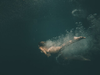 Fototapeta na wymiar European young woman diving and swimming underwater in Croatia in mediterranean sea