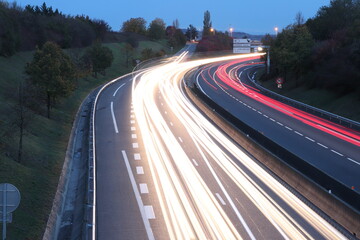 Trainées de lumières de phares de voitures au coucher du soleil sur le boulevard urbain sud de Lyon, ville de Corbas, département du Rhône, France
