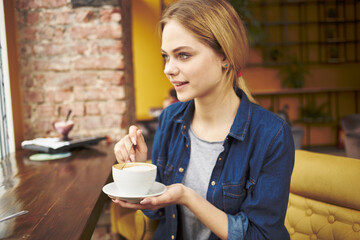 Pretty woman sitting at a cafe table with a cup of coffee breakfast lifestyle