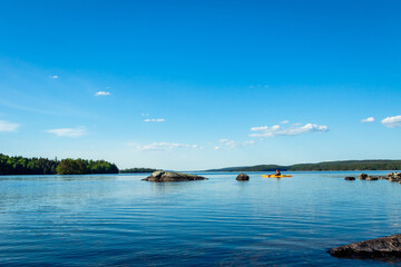 Kanu auf einem See in Schweden, Felsen im Vordergrund, blauer Himmel