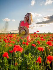 Young girl in a red dress in a poppy field
