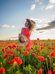 Young girl in a red dress in a poppy field
