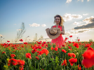 Young girl in a red dress in a poppy field
