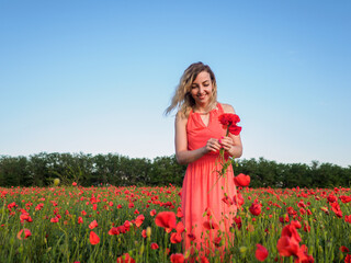 Young girl in a red dress in a poppy field
