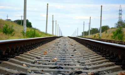 the track of the railway goes into the distance. rails and sleepers are visible, trees and bushes grow along the edges of the road