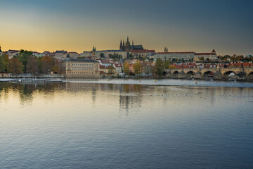 Fototapeta na wymiar beautiful view of the sights of Prague Castle and St. Vitus Cathedral and Charles Bridge and the level of the Vltava River in the center of Prague at sunset. the sun colors the sky orange