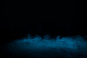 Abstract blue smoke moves on black background. Mystical swirling smoke rolling low across the ground.