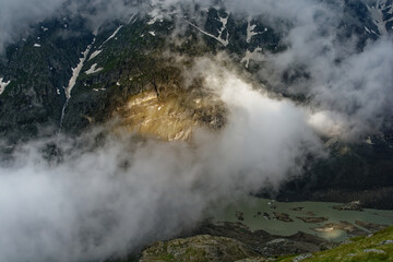 Clouds and fog in the Alps, the highest mountains in Europe. Austria or Italy in autumn, bad weather and rocks in cold windy day