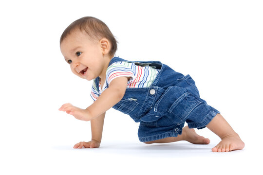 A crawling baby boy dressed in overalls and isolated on white background