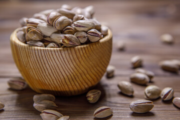 Pistachios in a Cup on a wooden background.  Place for text. Nuts close up