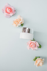 Creative  floral   organic natural dermatology cosmetic hygienic cream with flowers skincare product in glass jar on  pastel blue  background  of  roses  flowers