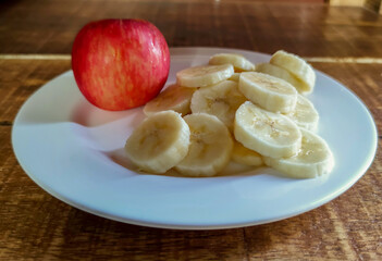 Naklejka na ściany i meble An apple and a sliced banana on wooden background