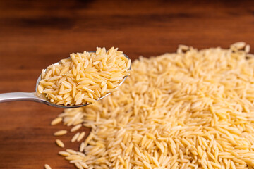Raw dry uncooked Orza Risoni pasta spaghetti noodle on white bowl wooden background for basil tomato pesto sauce Homemade Italian food organic whole wheat vegan spaghetti for a healthy meal