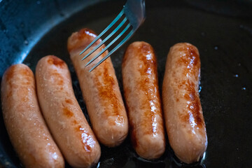 Cooking sausages in oil in a pan