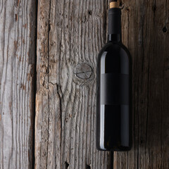 Close-up top view of bottle with red wine on rustic wooden background. Space for text. Vertical...