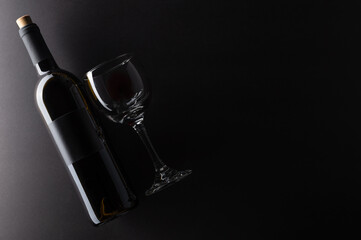 Top view of bottle and glass with red wine on dark grey background. Space for text. Horizontal...