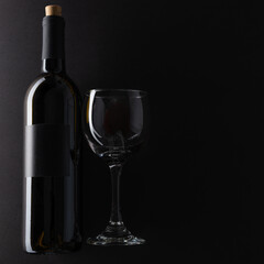 Bottle and glass with red wine on dark grey background. Space for text. Horizontal format. Template concept for your design and advertising company.