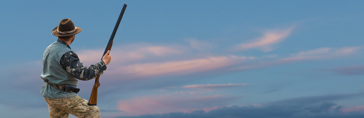 Silhouette of a hunter with a gun  against the sun, an ambush for ducks.