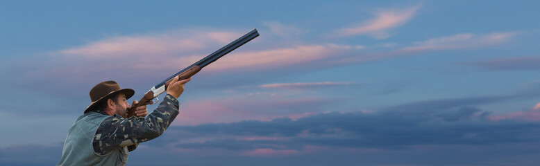 Silhouette of a hunter with a gun  against the sun, an ambush for ducks.