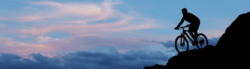 Conquering mountain peaks by cyclist in shorts and jersey on a modern carbon hardtail bike with an air suspension fork . Beautiful view from the mountain.