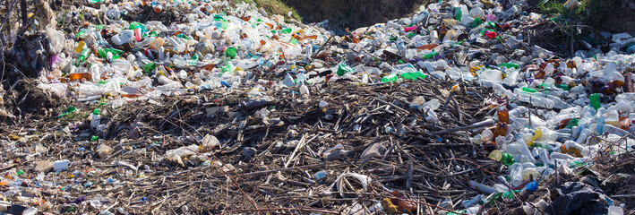 Obraz premium Plastic bags and bottles in a landfill. Unauthorized release of garbage, pollution of nature. The concept of environmental disaster.