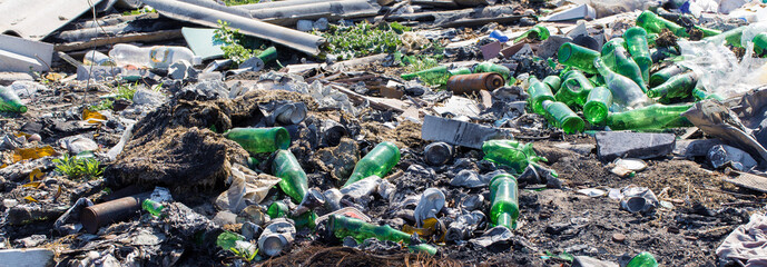 Plastic bags and bottles in a landfill. Unauthorized release of garbage, pollution of nature. The concept of environmental disaster.