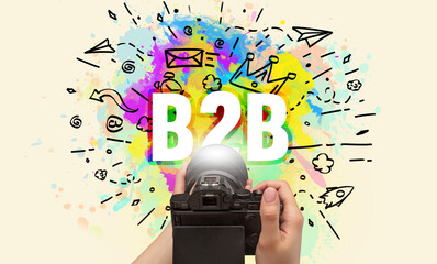 Close-up of a hand holding digital camera with abstract drawing and B2B inscription