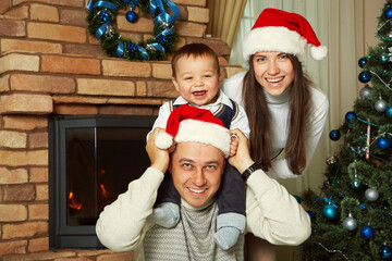 family celebrating Christmas at home. father, mother and child in Santa hats. New Year and xmas people