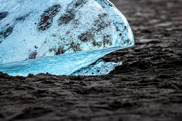 Closeup abstract view of blue glacier iceberg in Jokulsarlon lagoon lake diamond beach in Iceland with black sand on shore