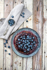 Traditional French tarte aux myrtilles with sweet blueberries and vanilla offered as top view on a design plate with rustic wooden background