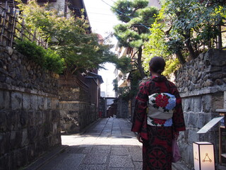 An Asian woman wearing a traditional Japanese kimono walking through the historic streets, Kyoto, Japan