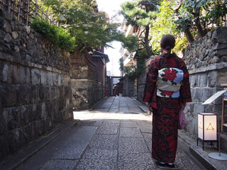 An Asian woman wearing a traditional Japanese kimono walking through the historic streets, Kyoto, Japan