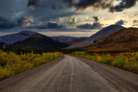 View of Scenic Road and Mountains on a Fall Day in Canadian Nature. Dramatic Sunset Sky Artistic Render. Taken near Tombstone Territorial Park, Yukon, Canada.