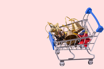 View of colorful Christmas decorations in toy shopping cart on red background. Christmas background.