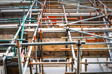 Closeup low angle view looking up abstract pattern lines of building wall construction scaffold scaffolding metal frame in city