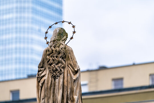 Immaculate conception statue of Virgin Mary with nimbus halo with modern skyscraper building in blurry blurred bokeh background at Church of St. Anthony of Padua, Warsaw Poland - Powered by Adobe