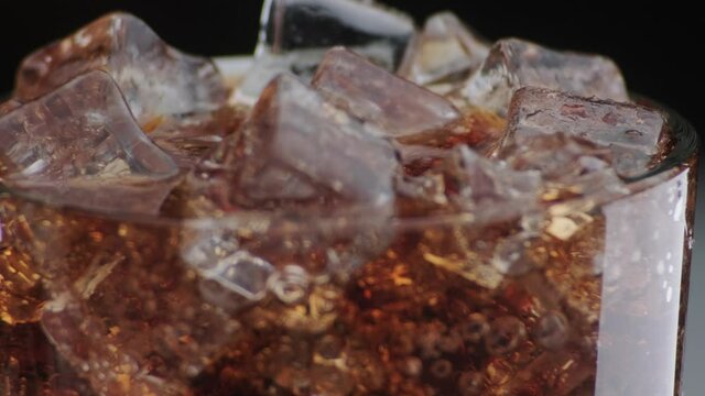 Ice Cubes and Bubbles in a Dark Drink with Condensation on Glass