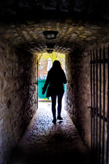 Fototapeta na wymiar Silhouette of woman person tourist walking in Quebec City, Canada near Lower old town with cobblestone street narrow alley Passage De La Batterie with light lamp