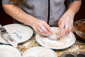 Woman cooking forming making piece of homemade mochi sticky glutinous Japanese rice cake dessert in kitchen with chocolate filling dirty hands