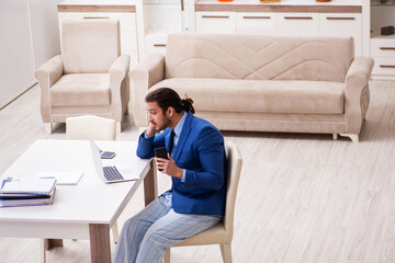 Young male employee working from house in self-isolation concept