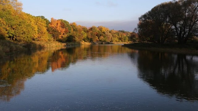 The sun rising on the autumn colored trees lining the Grand River. Shot in Waterloo, Ontario, Canada.