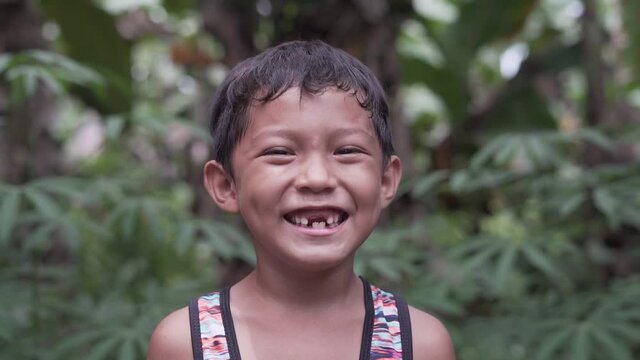 Close Up Slow Motion Video Portrait of a Handsome Cute Toothless Asian Filipino Kid Smiling into the Camera from the Rural Village in the Philippines with Extreme Happiness
