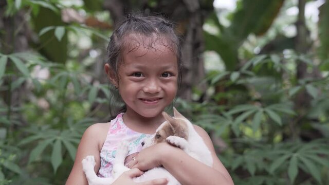 Close Up Video Portrait of a Pretty Asian Filipino Girl Smiling into the Camera while Holding a Cute Little Puppy Dog in the Philippines with Cheerful Happiness