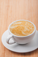 Close up white coffee cup with latte art on wood table at cafe.