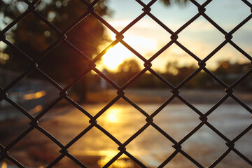 Fototapeta premium sunset through chain link fence with blue sky