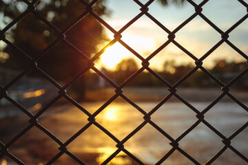 sunset through chain link fence with blue sky