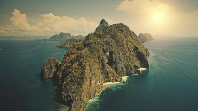 Uninhabited island at blue ocean bay at sun shine aerial view. Nobody wild nature scenery at amazing tropic mountainous islet of Palawan, El Nido, Philippines archipelago. Cinematic summer vacation