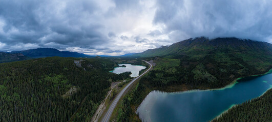 Panoramic View of Lakes from Above surrounded by Forest, alongside Scenic Road at Twilight. Aerial Drone Shot taken in Canadian Nature. Klondike Highway, South of Whithorse, Yukon, Canada.