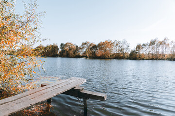 Old rustic wooden pier on the lake in sunny autumn evening. Selective focus. Shallow depth of field.