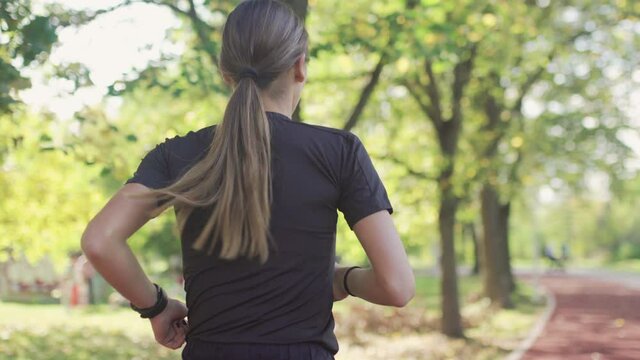 Fitness girl with ponytail running in the park. View from behind